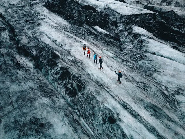 Groupe de personnes randonnant sur un glacier avec piolets et crampons