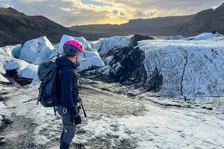 Randonneur avec sac à dos contemplant un paysage glaciaire accidenté au coucher du soleil