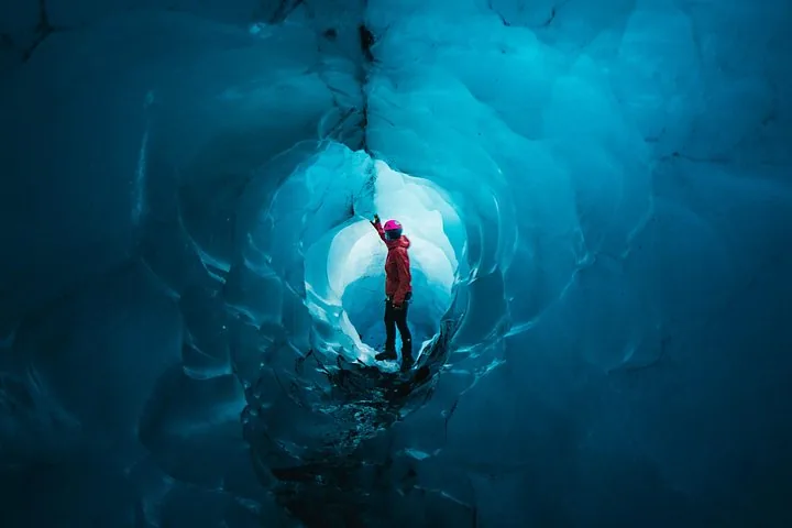 Personne explorant une superbe grotte de glace bleue à l'intérieur d'un glacier